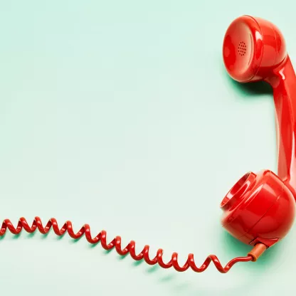 Red mid-century phone receiver on mint background with red coiled wire leading off canvas to the left